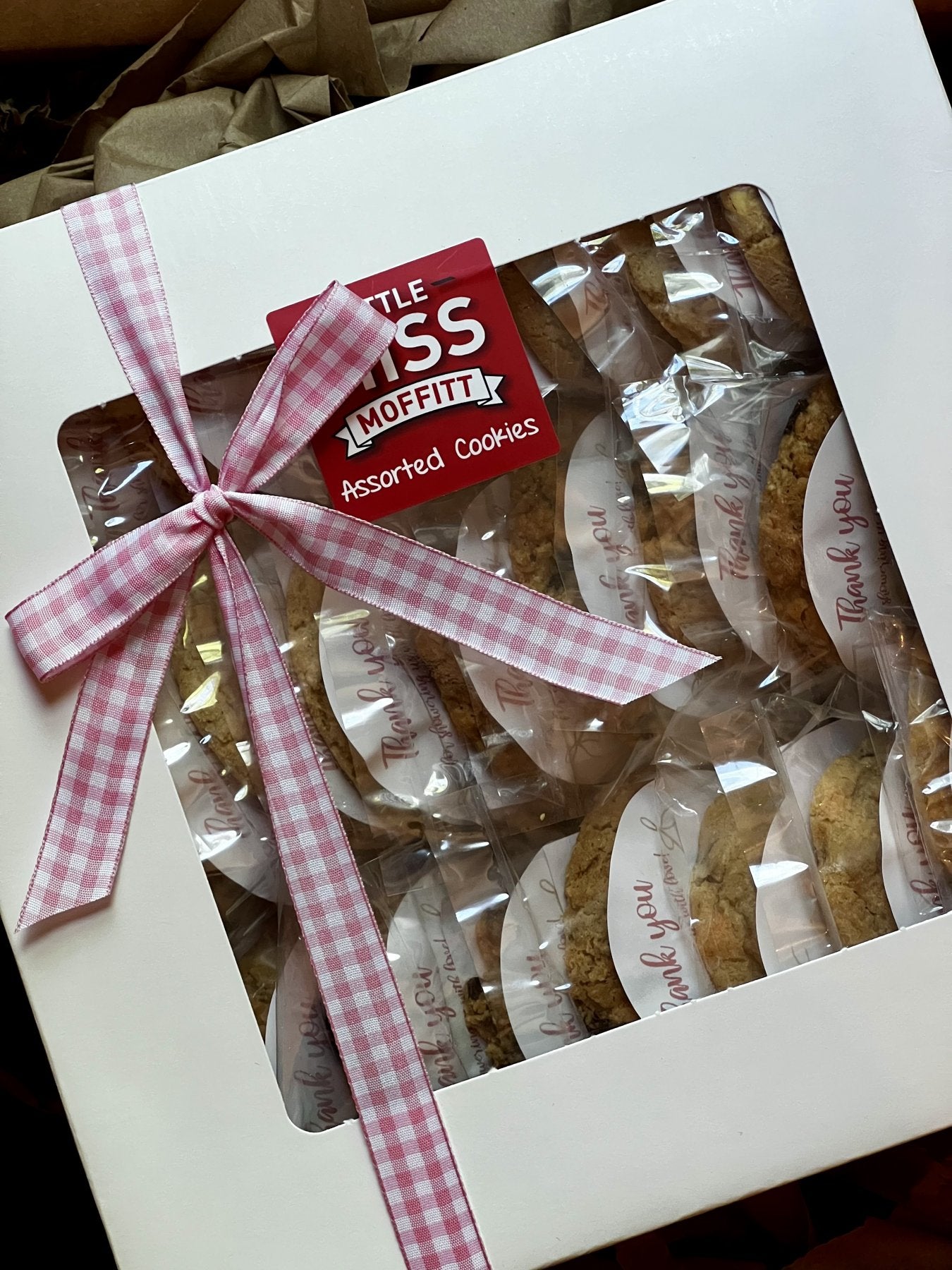 Cookie gift box with pink gingham ribbon holding individually wrapped thank-you cookies for a baby shower